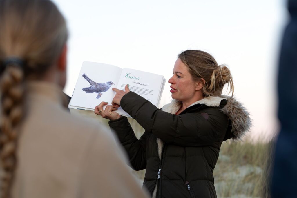 Marloes van Eilandmeisje laat een vogelboek zien tijdens de schemerwandeling op Terschelling