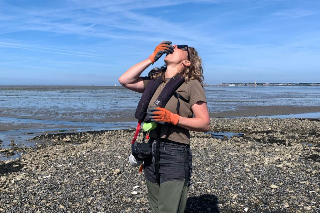 Jennifer proeft een oester op het wad bij Terschelling