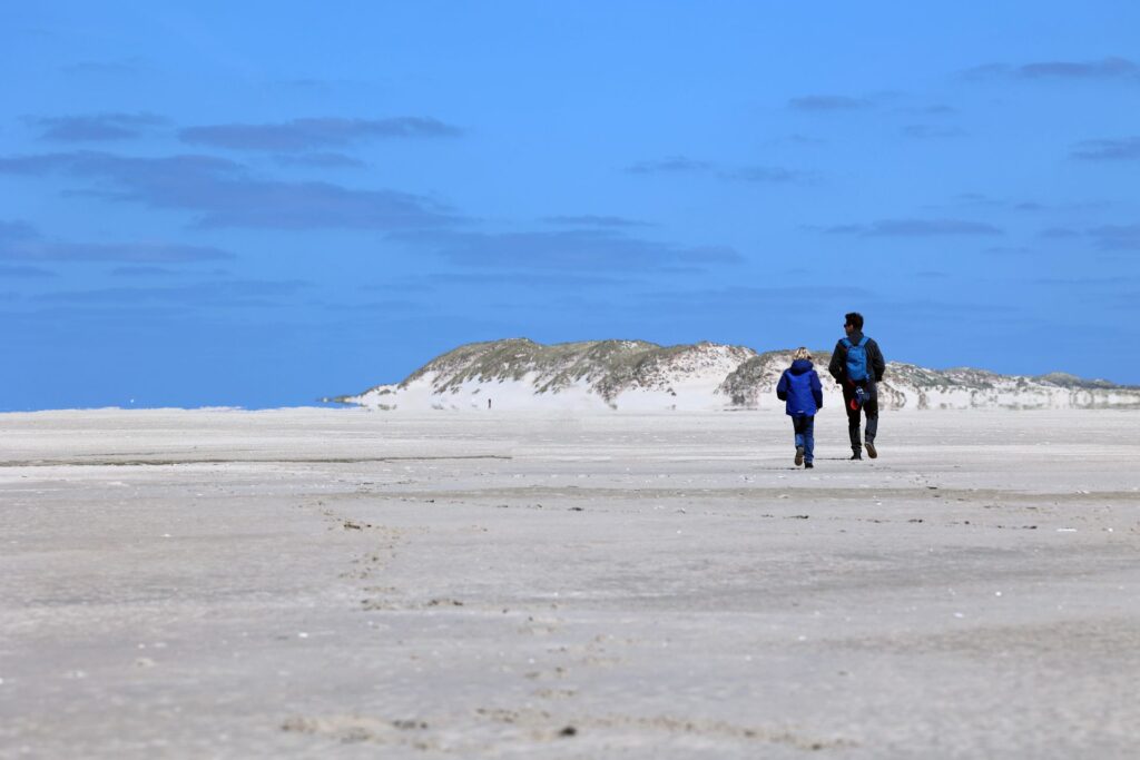 Man en zoon wandelen over het hoogste duin van de Noordsvaarder richting het Noordzeestrand, Terschelling