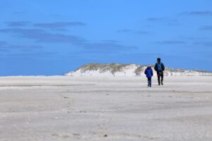 Man en zoon wandelen over het hoogste duin van de Noordsvaarder richting het Noordzeestrand, Terschelling